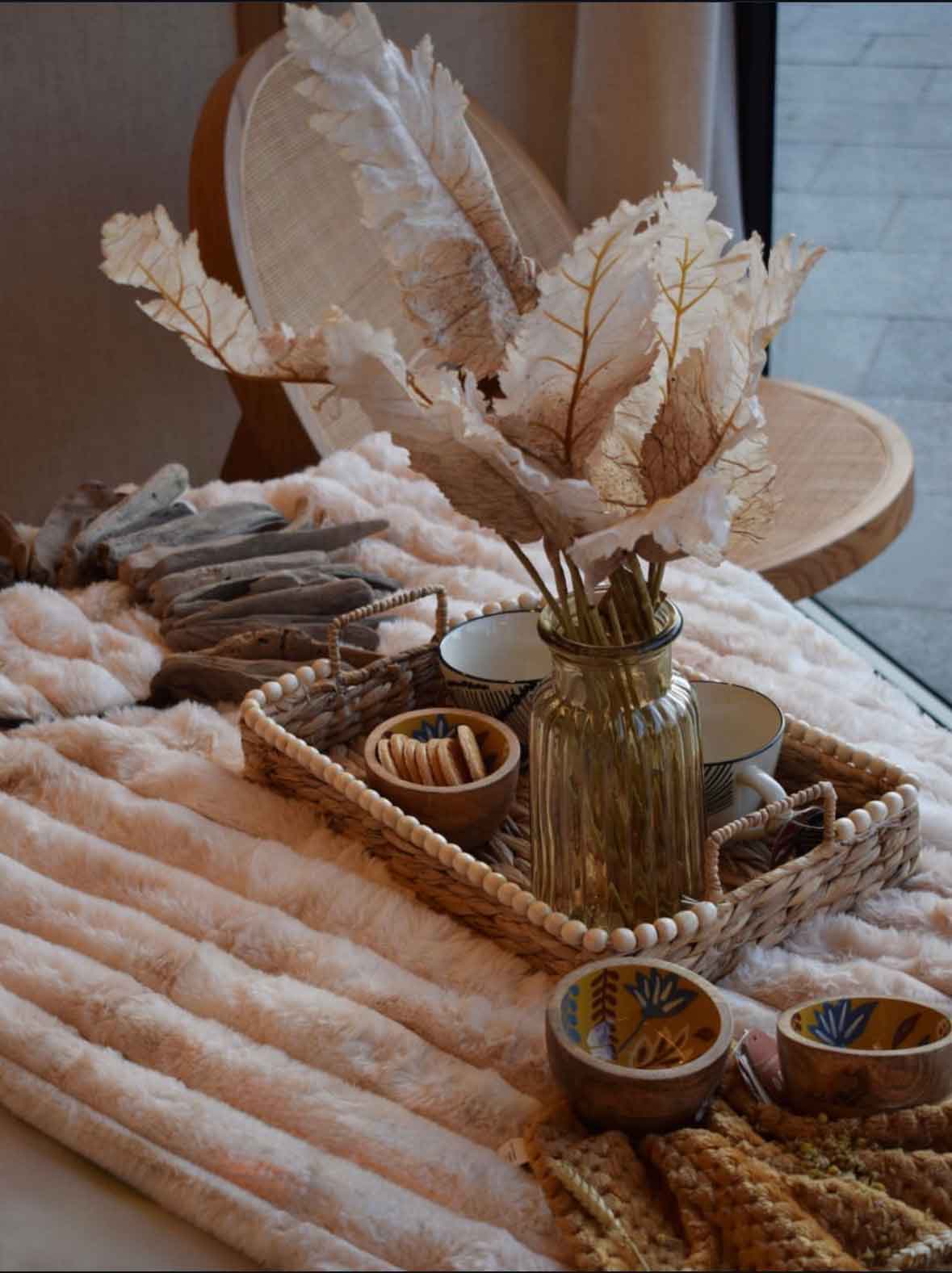 detalle wabi-sabi de bandeja con vajilla y hojas secas sobre manta de texturas suaves en suite de teca y piedra en Burgos