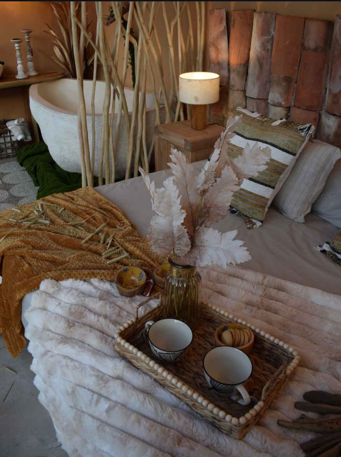 suite wabi-sabi en Burgos con cama, separador de ramas naturales y bañera de piedra al fondo