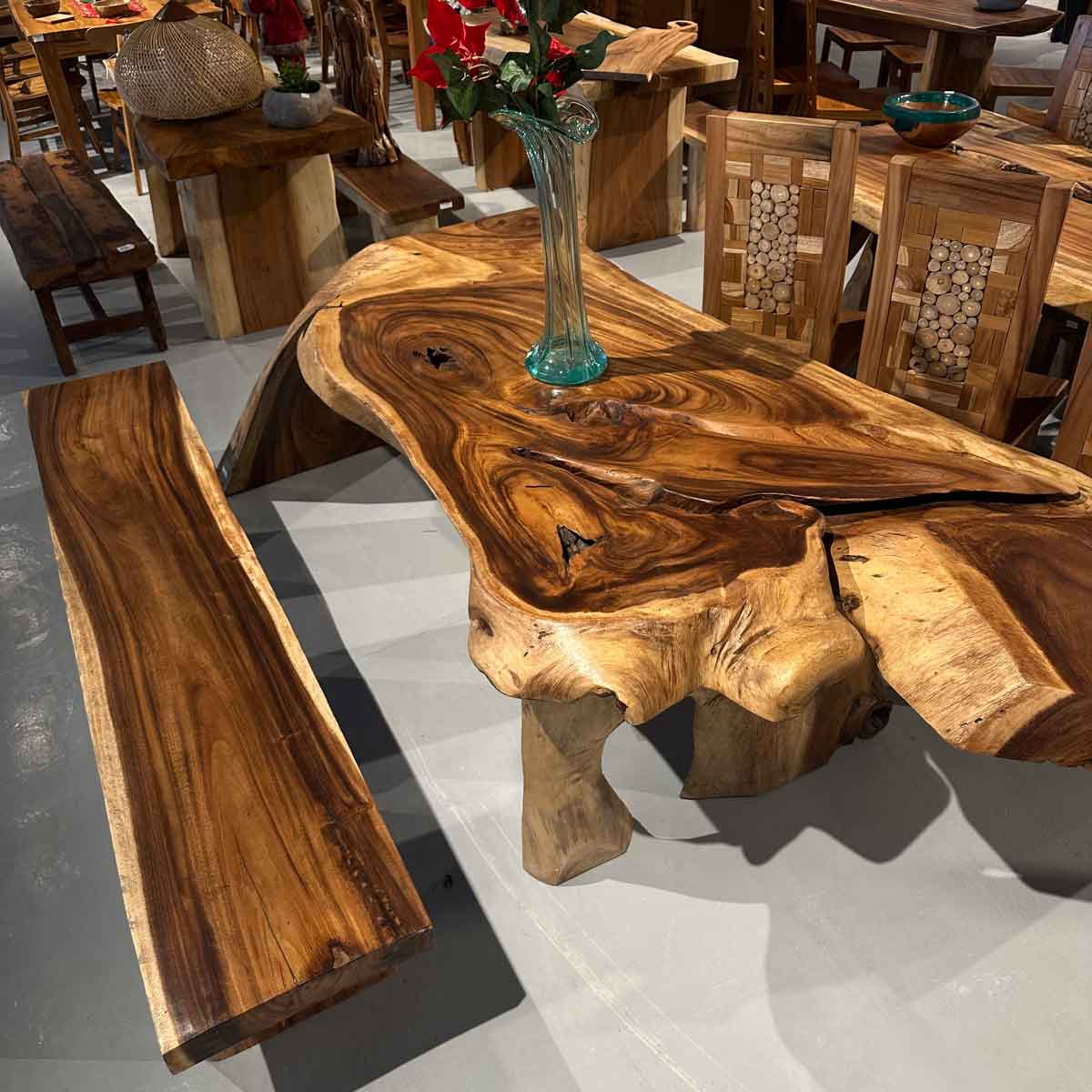 mesa de madera noble maciza con patas escultoricas y banco a juego en showroom de muebles
